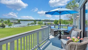 A deck with wicker furniture, a table, and a blue umbrella. - Moondance at BERNARD’S LANDING (moneta)
