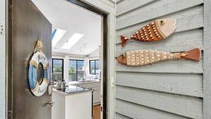 A modern kitchen with a central island, a door with a 'Moon Dance' sign, and two decorative fish on the wall. - Moondance at BERNARD’S LANDING (moneta)