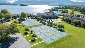An aerial view of a residential area with multiple tennis courts, a parking lot, and houses. - Moondance at BERNARD’S LANDING (moneta)