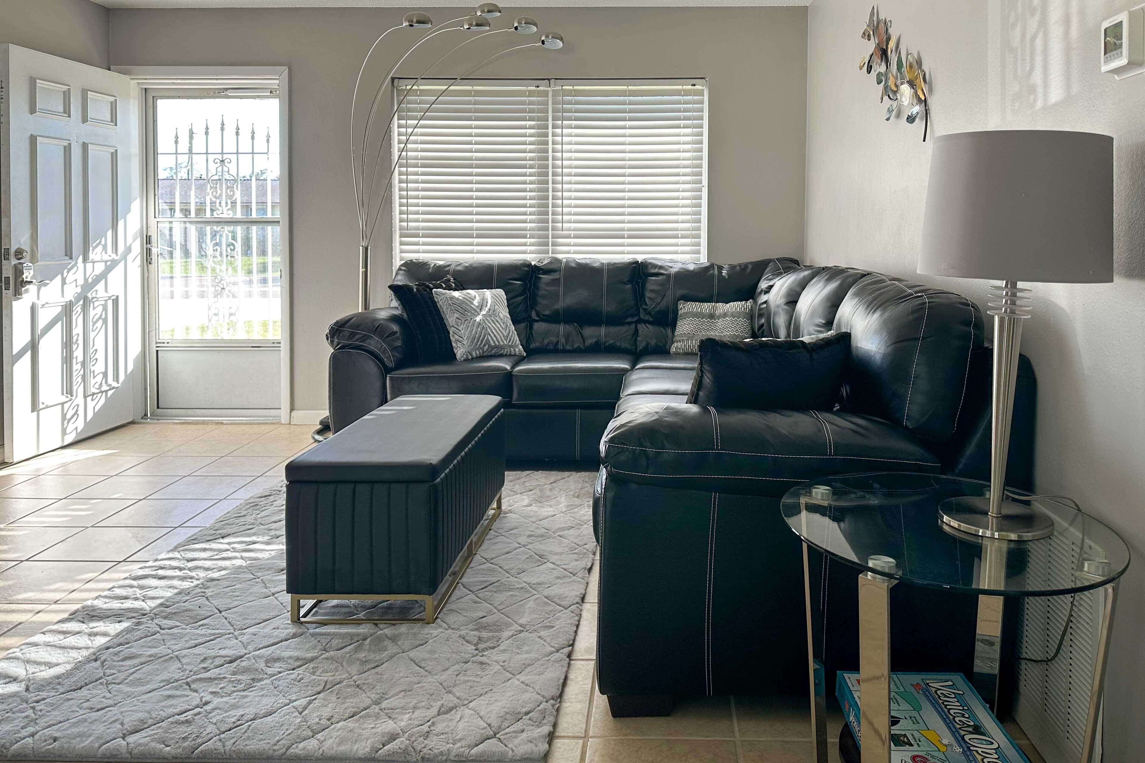 A modern living room with a leather sectional sofa, a glass coffee table, and a quilted rug.