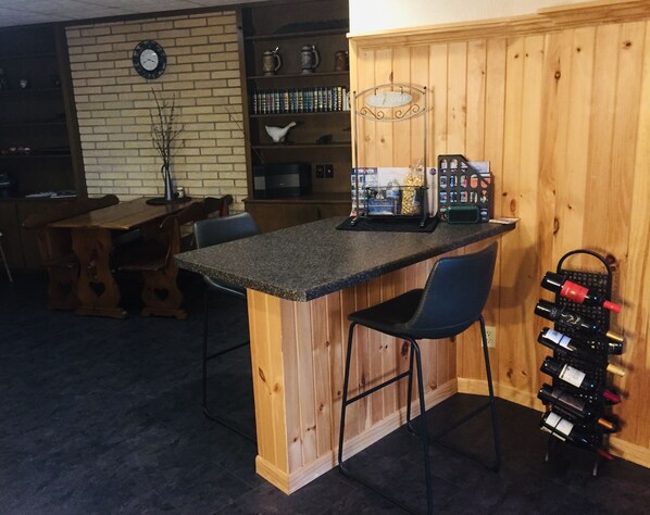 A kitchen with a wooden island, bar stools, a wine rack, and a clock on the wall.