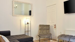 A modern living room with a grey sofa, a matching armchair, a coffee table, and a flat-screen TV mounted on the wall. - 3 bedroom accommodation in Alnwick (Alnwick)