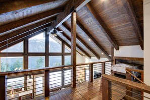 Estada d'una habitació amb sostre alt de fusta i grans finestres que donen vistes a les muntanyes.