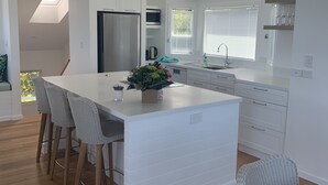 Una cocina moderna con una isla central, taburetes de bar y una mesa de comedor.