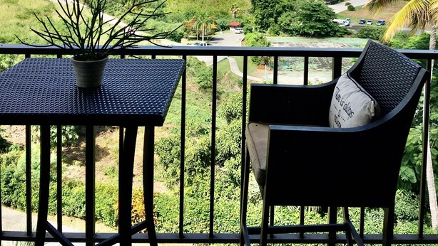 Een balkon met uitzicht op een kustlandschap, inclusief heuvels en een waterlichaam.