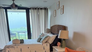 Een slaapkamer met een bed, een sofa, een nachtkastje, een lamp en uitzicht op de omgeving.
