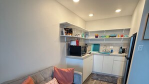 Een moderne keuken met witte kasten, een grijze aanrechtblad en een ingebouwde magnetron.