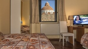 A hotel room with a bed, a desk with a chair, a television, and a window with curtains. - Hotel Il Giardino (Pisa)