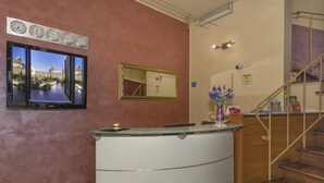 A reception area with a glass counter, a large mirror, and a wall-mounted clock. - Hotel Il Giardino (Pisa)