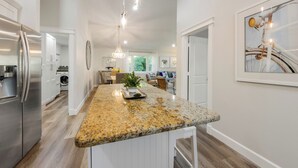 A modern kitchen with granite countertops, stainless steel appliances, and pendant lighting.