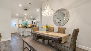 A dining area with a wooden table, wicker chairs, and a chandelier.