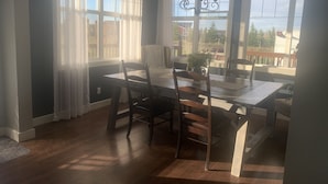 Un comedor con mesa de madera, sillas y una araña.