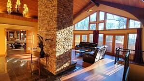 A spacious living area with a stone fireplace, leather seating, and large windows providing natural light.