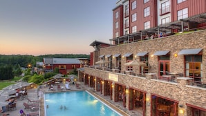 A hotel with a swimming pool, outdoor seating, and a red building with multiple balconies.