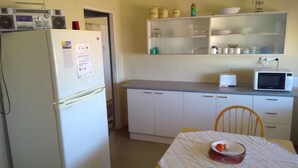 Cocina compacta con refrigerador, microondas y una pequeña mesa de comedor con una silla.