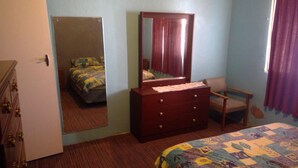 Un dormitorio con cama, cómoda, silla y espejo.