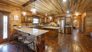 Una cocina amplia con paredes de madera y una isla grande, equipada con electrodomésticos modernos y taburetes de bar.