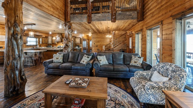 Un interior espacioso de madera con dos sofás de cuero, un sillón estampado y una mesa de centro de madera.