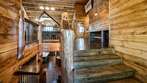 Interior de madera con una escalera, paredes de madera y un letrero que indica un bar.