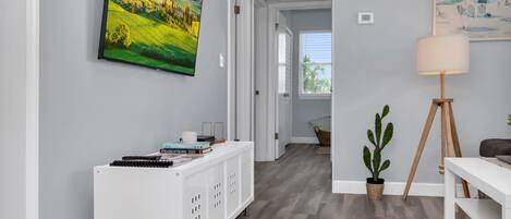 Un interior moderno con una consola blanca, una planta de cactus y un cuadro de un paisaje.