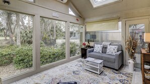 A spacious living room with large windows, a sofa, a coffee table, and a view of the outdoors. - Sunset Rentals | Kingston Dunes 80 (Hilton Head Island)