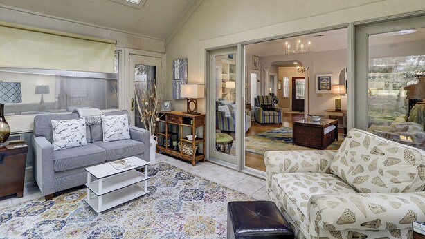 A spacious living room with a high ceiling, a large window, and a view into the dining area. - Sunset Rentals | Kingston Dunes 80 (Hilton Head Island)