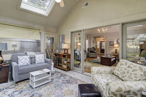 A spacious living room with a high ceiling, a large window, and a view into the dining area. - Sunset Rentals | Kingston Dunes 80 (Hilton Head Island)