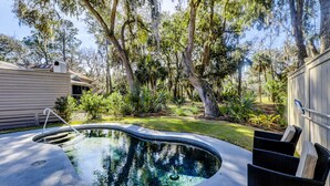 A swimming pool with a curved edge, surrounded by a grassy area and trees. - Sunset Rentals | Kingston Dunes 80 (Hilton Head Island)
