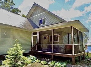 Ein Haus mit einer Veranda, einem kleinen Fenster und einer Tür.