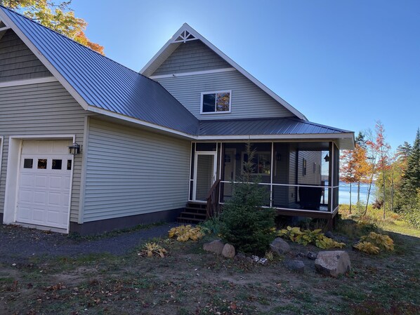 Ein Haus mit Garage, überdachter Veranda und Seeblick.