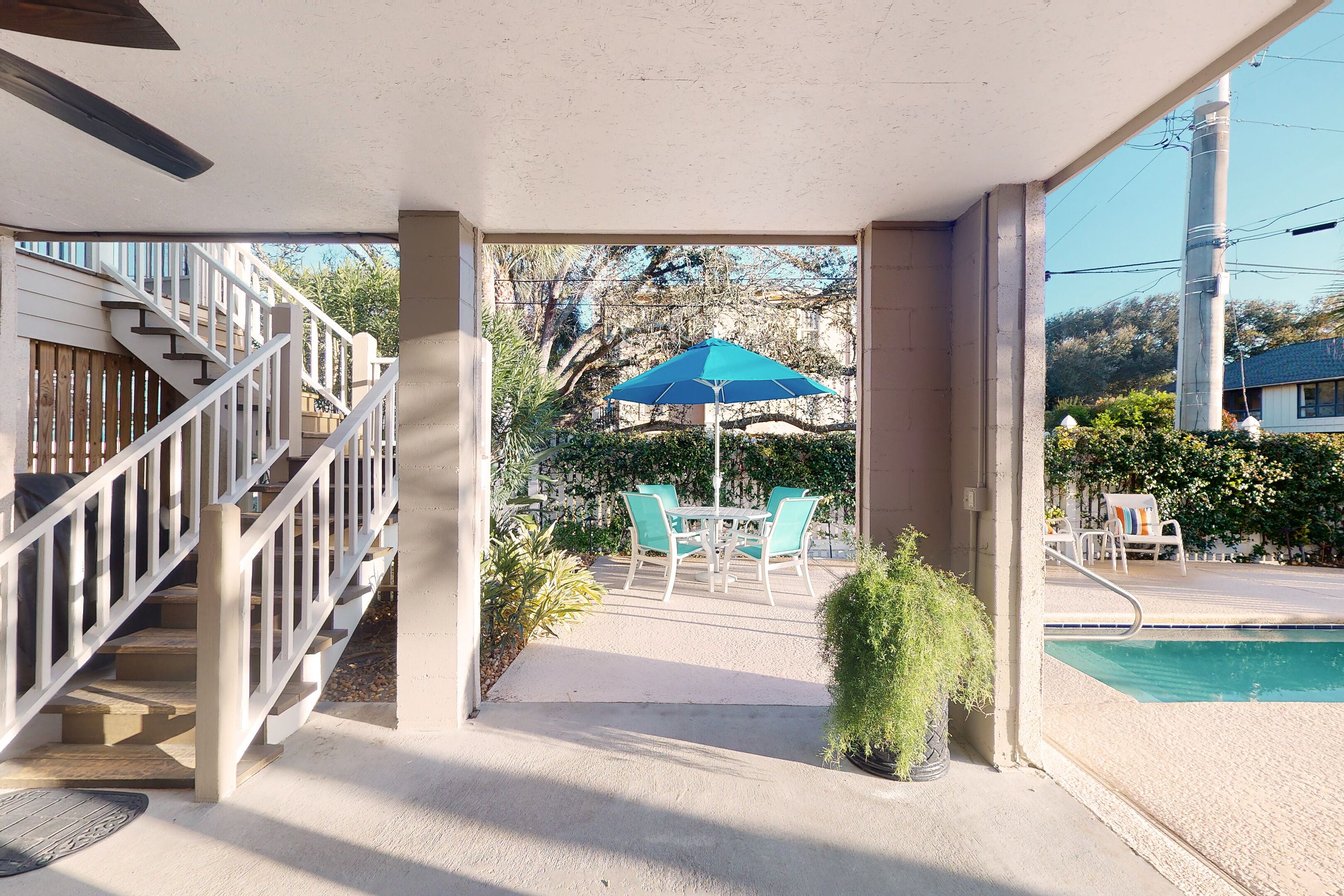 Ein überdachter Außenbereich mit Pool, Treppe und Tisch mit Stühlen.