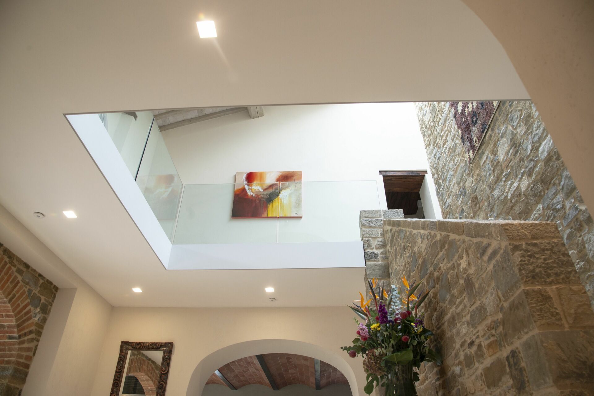 Ein modernes Interieur mit Oberlicht, Steinwand und einem gerahmten Spiegel.
