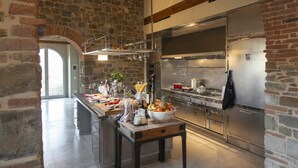 Uma cozinha espaçosa com uma ilha grande, eletrodomésticos de aço inoxidável e um painel de parede de pedra.
