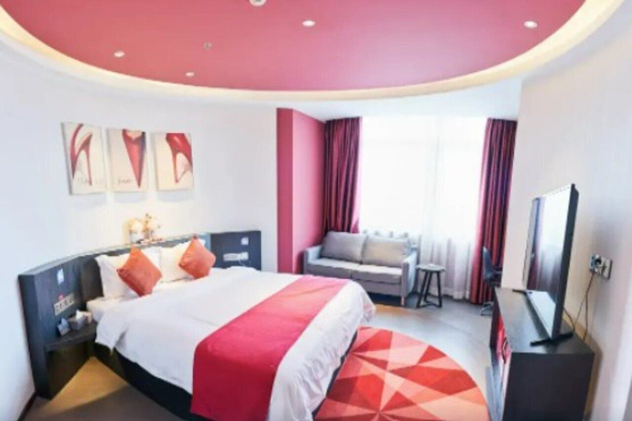 A hotel room with a bed, a TV, a small table, and a sofa.