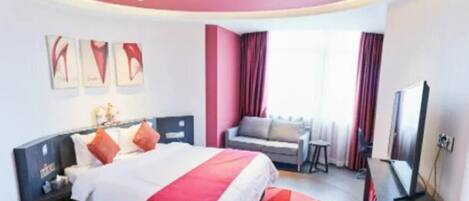 A hotel room with a bed, a TV, a small table, and a sofa.