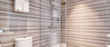 Une salle de bain moderne avec un mur recouvert de carreaux à rayures, une douche en verre et des toilettes blanches.