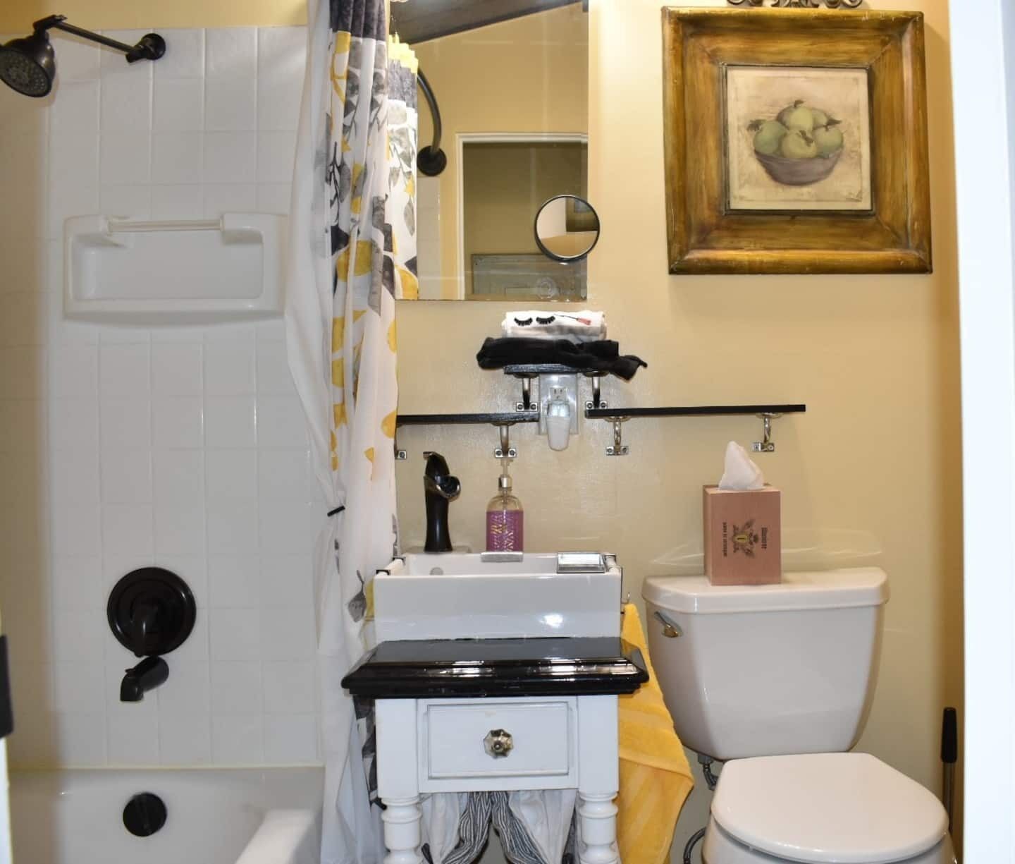 Une salle de bain avec une baignoire, des toilettes, un lavabo et un tableau encadré au mur.