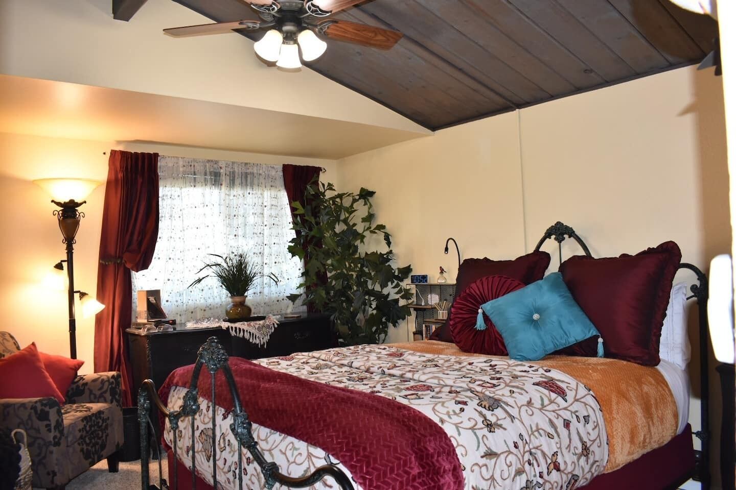 A bedroom with a bed, a desk, a chair, a lamp, and a ceiling fan.