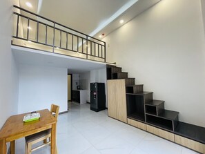 A modern apartment with a dining area, kitchen, and a staircase leading to an upper level.