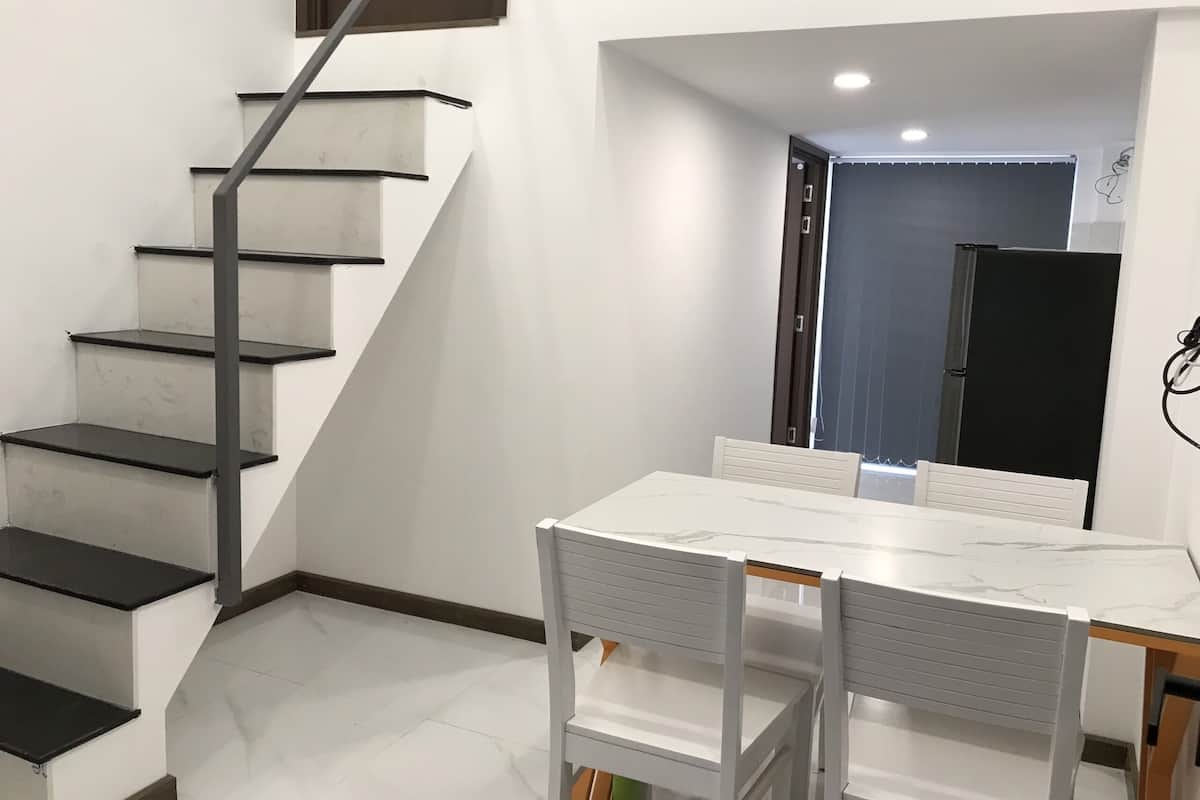 Interior moderno com escada, mesa de jantar e cadeiras.