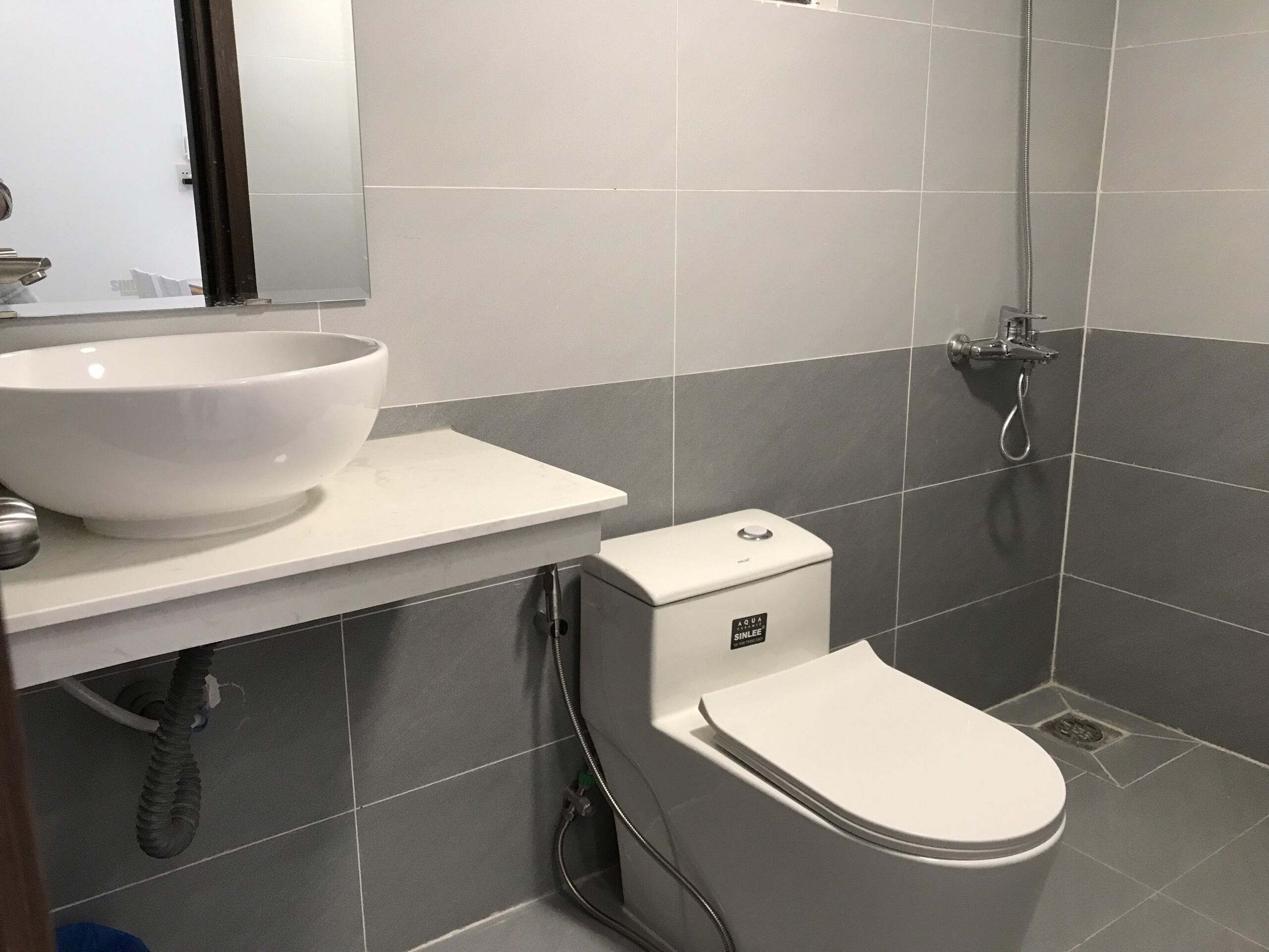 Une salle de bain moderne avec des toilettes blanches, un grand lavabo blanc et un espace douche.
