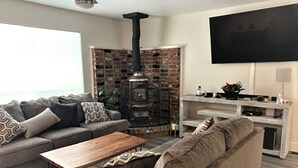 En stue med sofa, sofabord, pejs og tv ophængt på væggen.