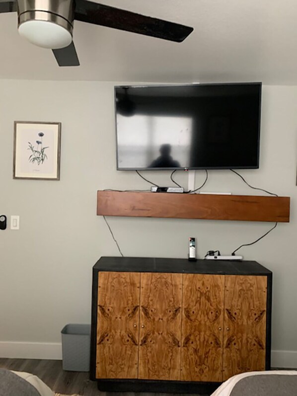 A modern living room with a flat-screen TV mounted on the wall, a wooden cabinet below, and a ceiling fan. - LAKE TAHOE HAVEN VACATION HOME (South Lake Tahoe)