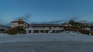 Una proprietà fronte spiaggia con un edificio grande dotato di numerosi balconi e un patio coperto.