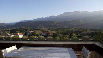 Une terrasse avec une table et des chaises donnant sur un paysage montagneux parsemé de maisons.