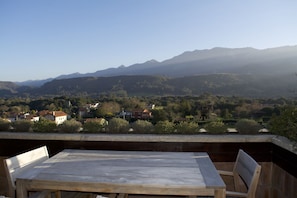 Une terrasse avec une table et des chaises donnant sur un paysage montagneux parsemé de maisons.
