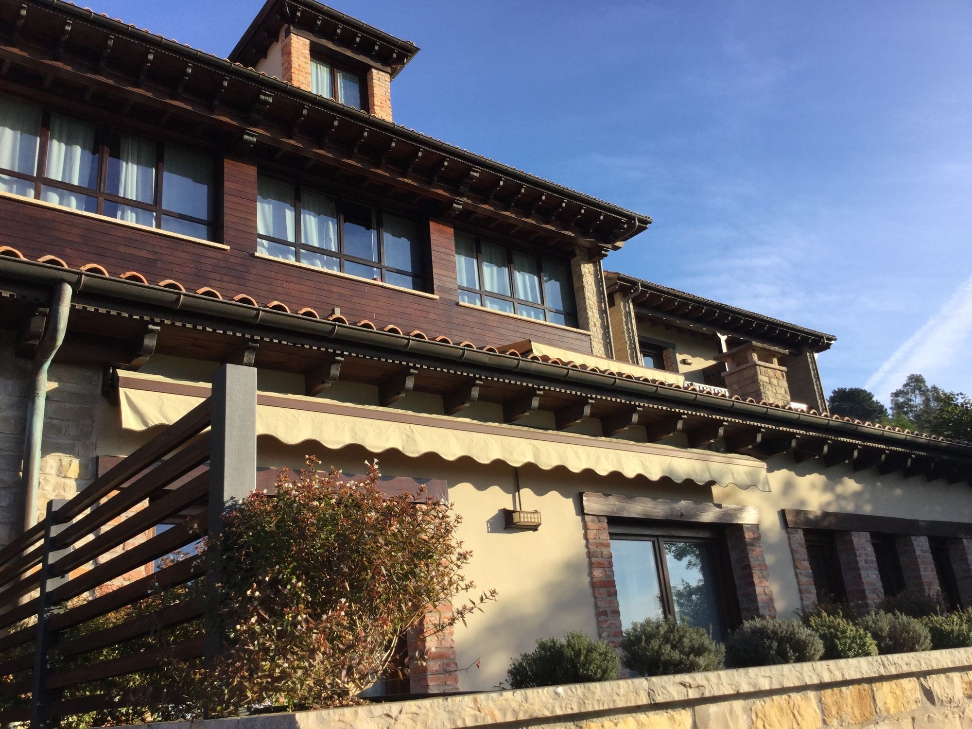 Un immeuble à plusieurs étages, de style architectural traditionnel, doté d’un balcon avec une balustrade en bois et d’un socle en pierre.
