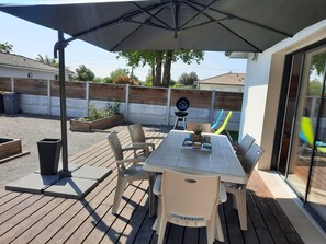 Een terras buiten met een tafel en stoelen, een barbecue en een glijbaan op de achtergrond.