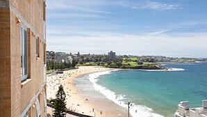 A coastal cityscape with a beach, buildings, and a clear sky.