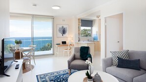 A modern living room with a large window, a dining area, and a kitchen.